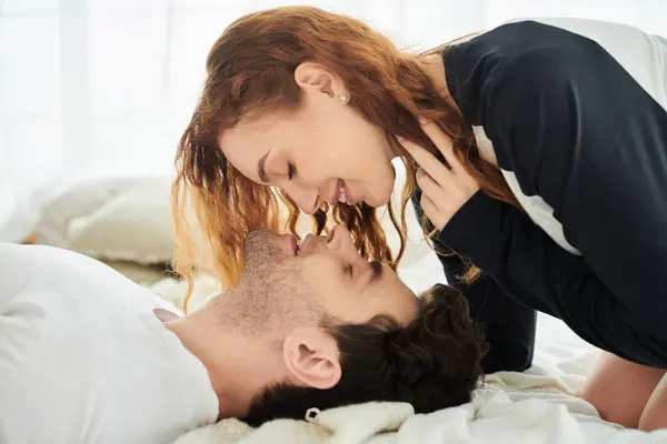 Un homme et une femme se détendent ensemble sur un lit confortable dans leur chambre, profitant d'un moment paisible et intime. — Photo de stock