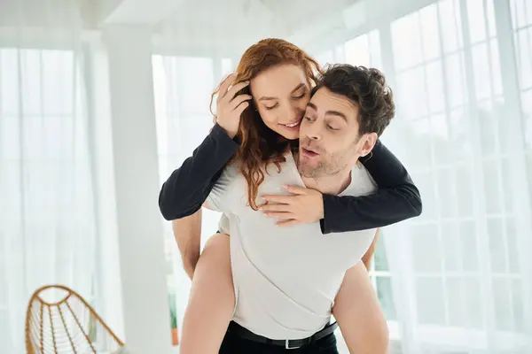 A man holds a woman in his arms, surrounded by a warm and intimate atmosphere in a bedroom. — Stock Photo