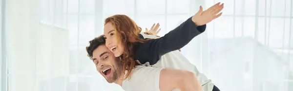 A man supporting a woman on his back, showing strength and unity in their relationship as they spend time together. — Stock Photo