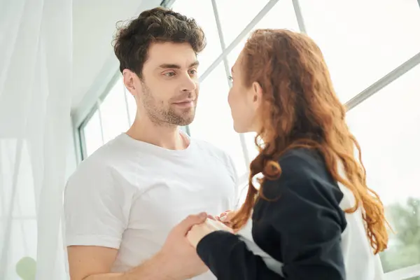 Um homem e uma mulher estão juntos perto de uma janela, compartilhando um momento de intimidade e conexão. — Fotografia de Stock