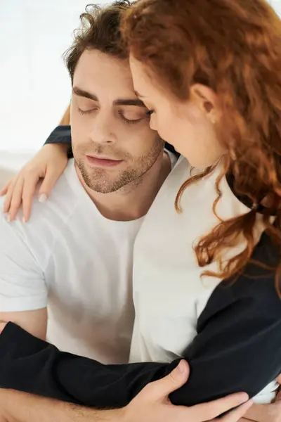 Мужчина и женщина нежно обнимают друг друга в уютной спальне, разделяя момент любви и связи. — стоковое фото
