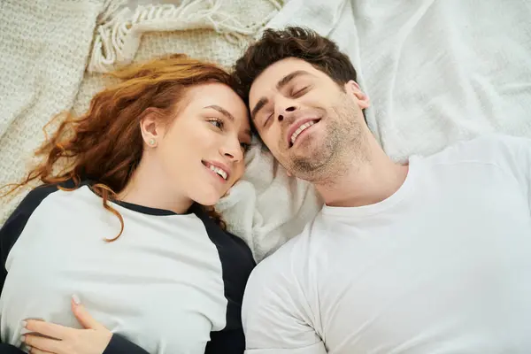 A man and a woman relax together on a bed in a cozy bedroom, enjoying each others company in a peaceful moment. — Stock Photo