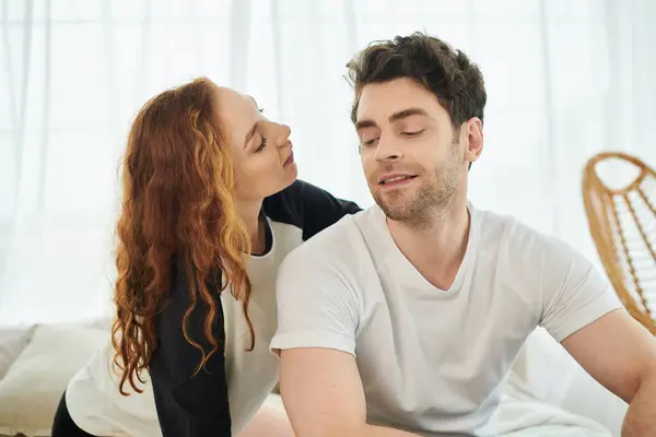 Um homem e uma mulher sentam-se pacificamente em uma cama em um quarto, desfrutando uns dos outros da companhia em um momento sereno de união. — Fotografia de Stock