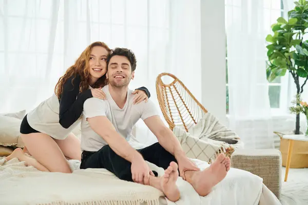 Un homme et une femme s'assoient paisiblement sur un lit douillet, profitant mutuellement de la compagnie dans leur chambre. — Photo de stock