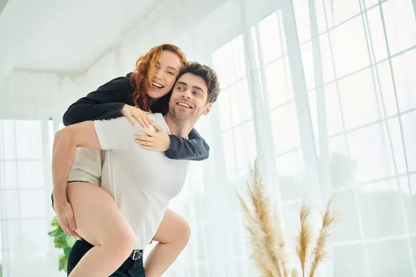 Un homme tient tendrement une femme dans ses bras, exprimant amour et connexion dans un cadre de chambre confortable. — Photo de stock