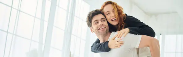 A man tenderly carries a woman in his arms in a bedroom setting, showcasing love and support. — Stock Photo