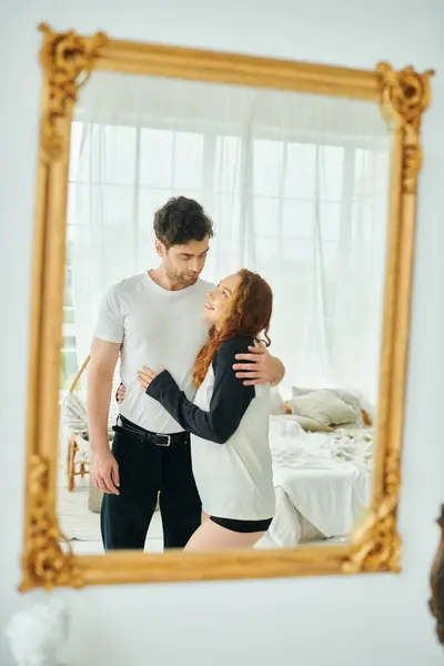 Un uomo e una donna in piedi insieme davanti a uno specchio, guardando le loro riflessioni e godendo di un momento di insieme. — Foto stock