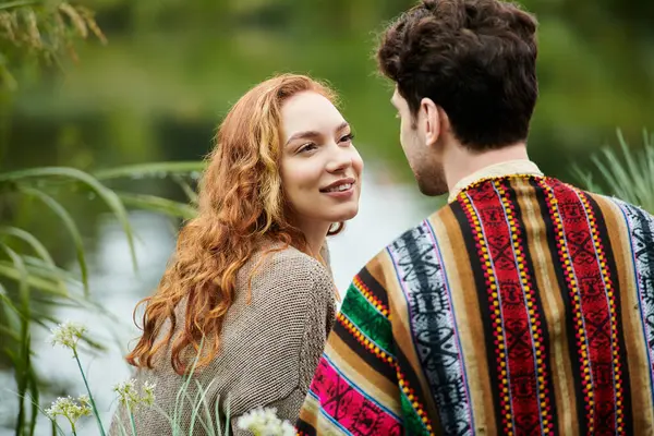 Um homem e uma mulher elegantes de traje boêmio estão juntos em um exuberante parque verde, exalando amor e conexão. — Fotografia de Stock