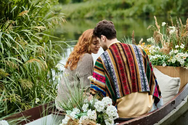 Ein Mann und eine Frau in Boho-Klamotten treiben in einem mit Blumen geschmückten Boot durch einen üppig grünen Park. — Stockfoto
