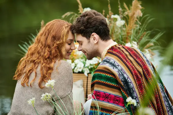 A man and a woman, dressed in boho style clothes, sit together in a lush green park, radiating romantic and carefree vibes. — Stock Photo