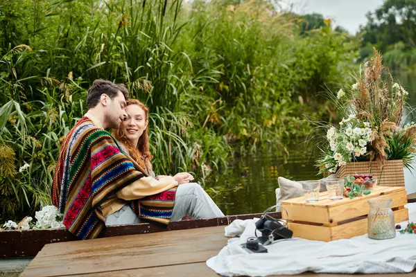 A couple in boho style attire enjoying a romantic boat ride in a serene green park setting. — Stock Photo