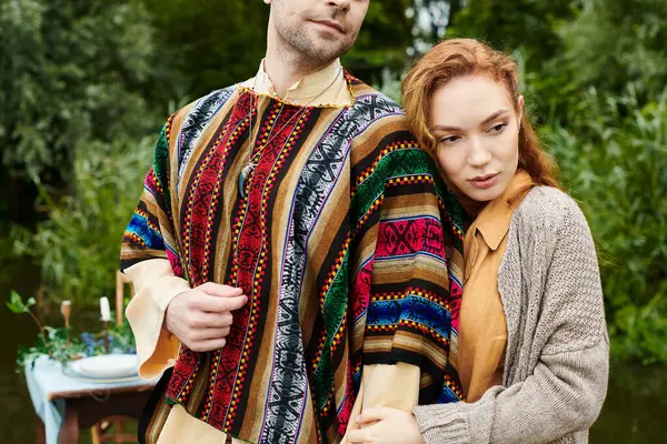 A man and woman in boho style clothing stand closely together in a green park setting, exuding love and connection. — Stock Photo
