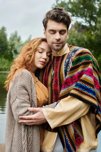 A stylish couple dressed in boho clothing stands next to each other in a serene green park setting, exuding love and connection. — Stock Photo