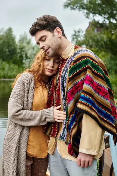 Un uomo e una donna in abito boho in piedi insieme in un lussureggiante parco verde, creando una scena serena e romantica. — Foto stock