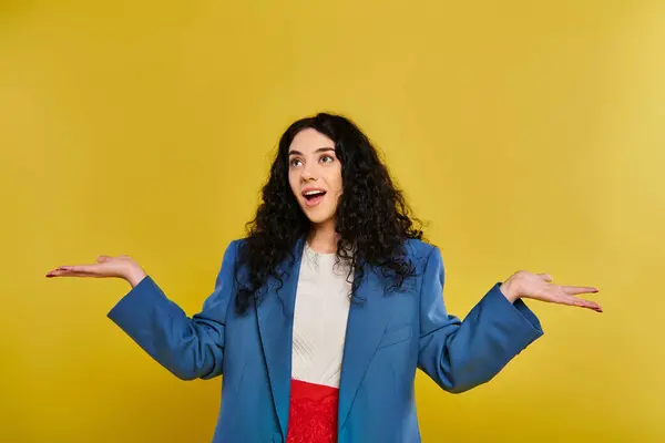 Una joven con el pelo rizado, con una chaqueta azul, extiende sus manos, mostrando una gama de emociones. - foto de stock