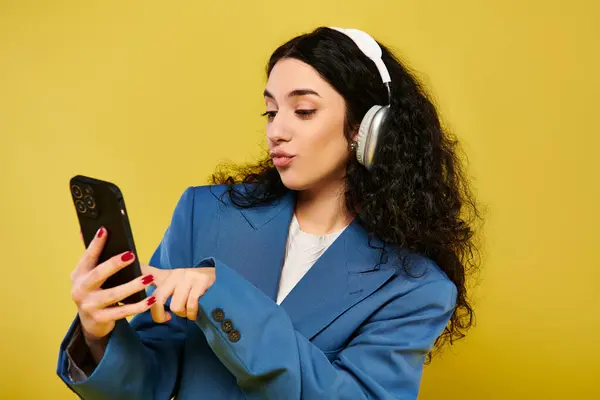 Eine junge brünette Frau mit Kopfhörern starrt auf ihr Handy, eingetaucht in die Musik, die durch ihre Ohren läuft. — Stockfoto