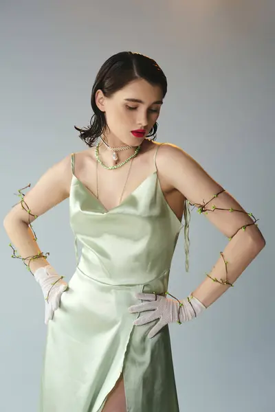 A young, beautiful woman with red lips poses in a green dress and gloves in a studio setting, exuding an enchanting aura. — Stock Photo