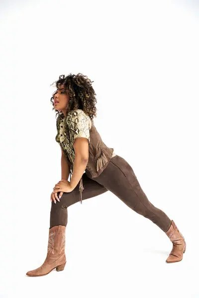 Mujer afroamericana con estilo con estampado animalista en traje posando en movimiento y mirando hacia otro lado - foto de stock