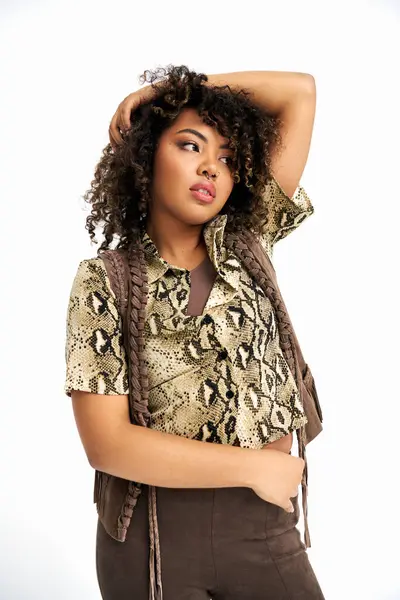 Polished chic african american woman with curly hair posing on white backdrop and looking away — Stock Photo