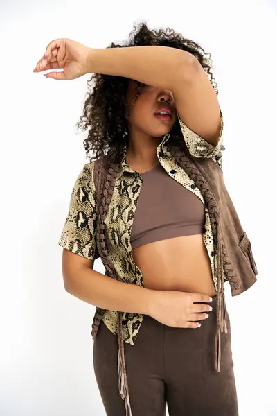 Elegant african american woman in attire with print on white backdrop covering eyes with arm — Stock Photo