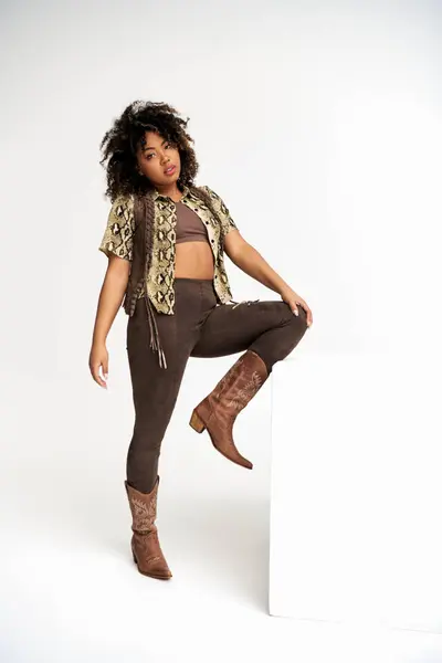 Elegant african american woman with animalistic print on attire next to cube looking at camera — Stock Photo