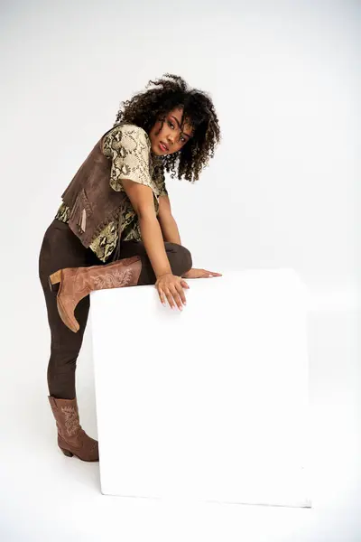 Alluring chic african american woman with animalistic print on attire next to cube looking at camera — Stock Photo