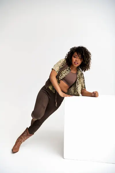 Cheerful african american woman with animalistic print on attire next to cube looking at camera — Stock Photo