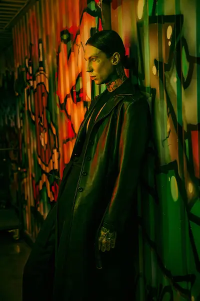 Un hombre al lado de una colorida pared cubierta de graffiti - foto de stock