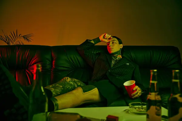 Ein Mann sitzt auf einer Couch und trinkt ein Getränk — Stockfoto