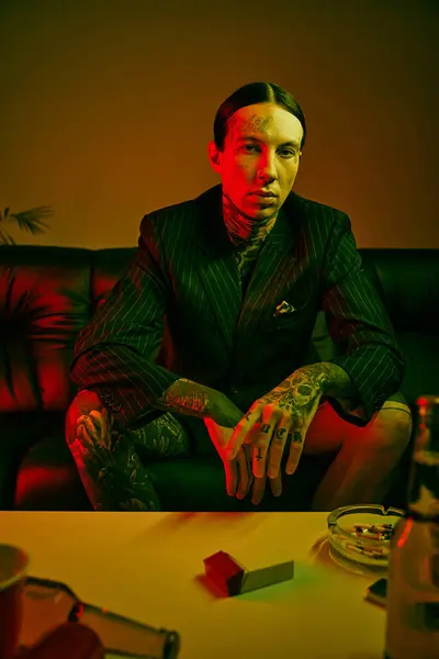 A man with tattoos sitting on a couch — Stock Photo