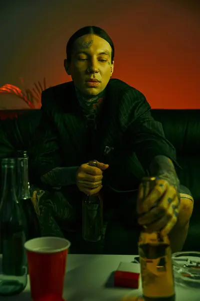Un hombre sentado en una mesa con una botella de alcohol - foto de stock