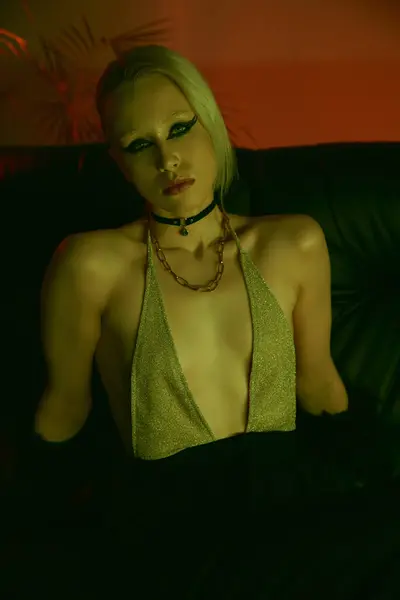 Uma mulher usando um top verde está sentada em um sofá — Fotografia de Stock