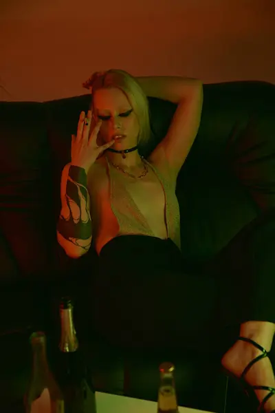 Mujer sentada en un sofá, fumando cigarrillo en una fiesta o discoteca - foto de stock