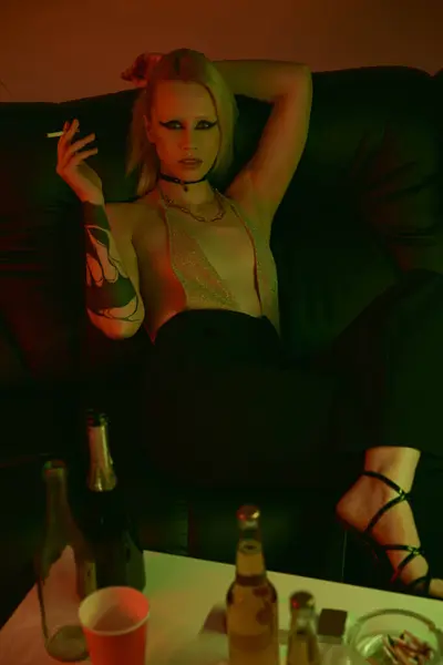 Una mujer sentada en un sofá, fumando un cigarrillo - foto de stock