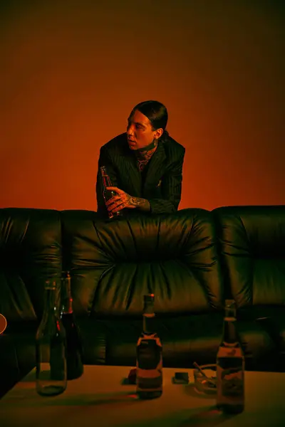 Male sitting on top of couch near alcohol bottles — Stock Photo