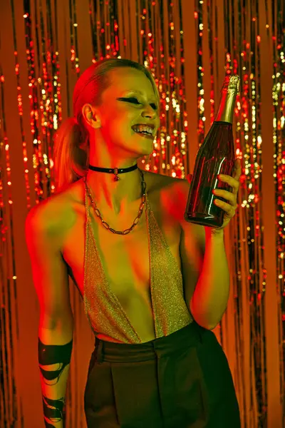 Uma mulher segurando uma garrafa na mão em uma animada festa de rave ou boate — Fotografia de Stock
