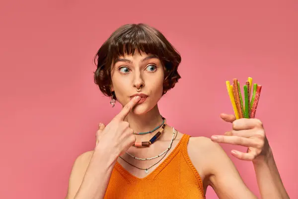 Curiosa menina perfurada em seus 20 anos com cabelo curto segurando monte de doces doces e azedos na mão — Fotografia de Stock