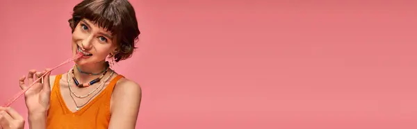 Bonito menina em 20s com dentes brancos e piercing mordendo doce e azedo doce tira em rosa, banner — Fotografia de Stock