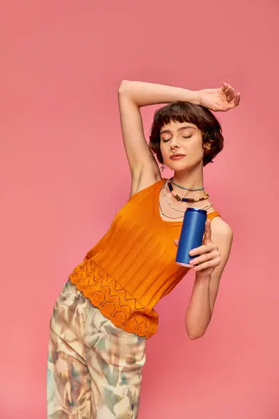 Pretty young woman with short brunette hair holding soda can while posing on pink, summer beverage — Stock Photo