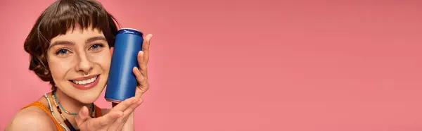 Bannière de jeune femme joyeuse avec des cheveux bruns courts tenant la canette de soda sur rose, boisson d'été — Photo de stock