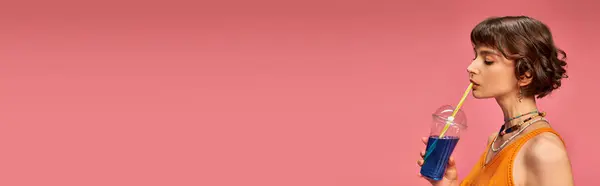 Jovem com cabelo curto morena bebendo refrescante coquetel de verão de palha em rosa, banner — Fotografia de Stock