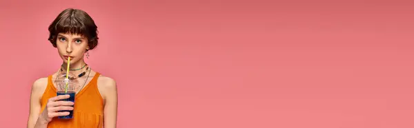 Jovem com cabelo curto morena bebendo azul refrescante coquetel de verão em rosa, banner — Fotografia de Stock