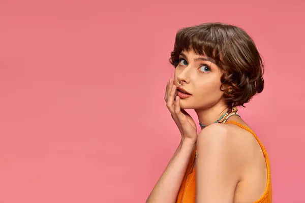 Pretty young woman in her 20s with short hair in vibrant tank top posing on pink background — Stock Photo