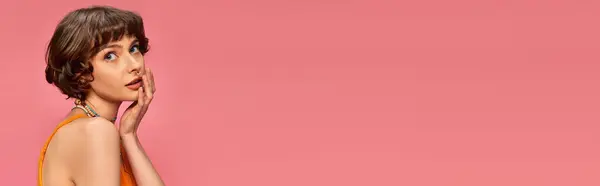 Jolie jeune femme dans la vingtaine avec les cheveux courts en débardeur vibrant posant sur fond rose, bannière — Photo de stock