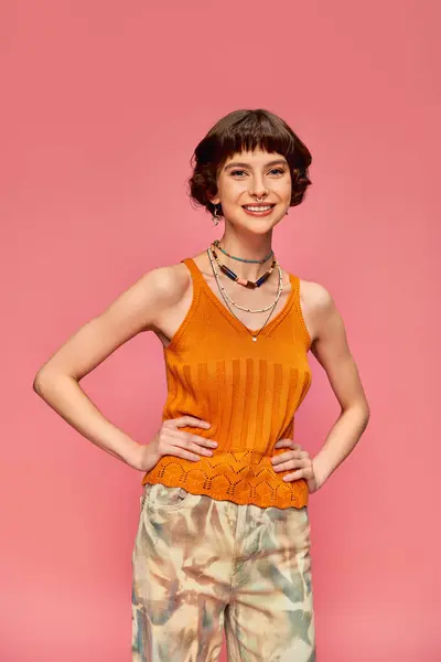 Positive young woman in her 20s with short hair in vibrant tank top posing on pink background — Stock Photo