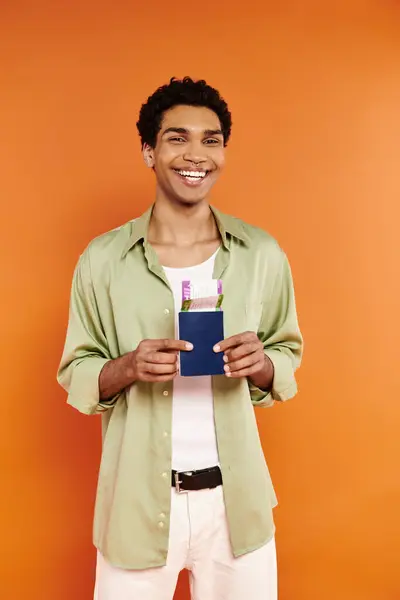 Joyous african american man in cozy attire holding passport with ticket and smiling at camera — Stock Photo