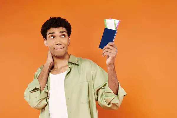 Beau joyeux homme afro-américain regardant billet et passeport en main sur fond orange — Photo de stock