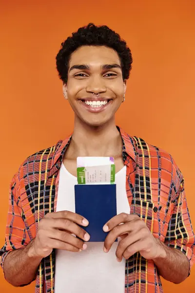 Cheerful african american man in stylish attire holding passport with ticket and smiling at camera — Stock Photo