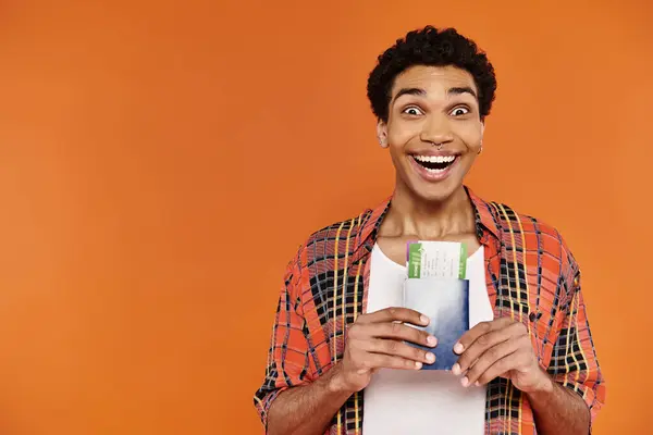 Alegre afroamericano hombre con elegante atuendo con pasaporte con billete y sonriendo a la cámara - foto de stock