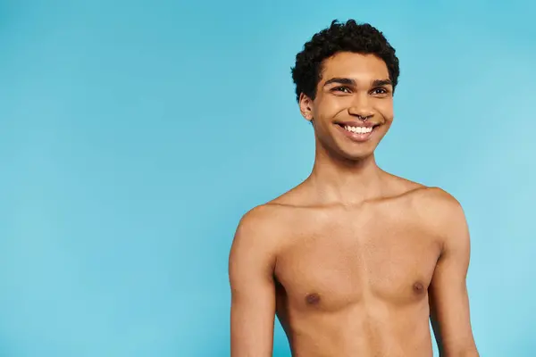 Alegre guapo africano americano hombre en azul natación troncos mirando hacia otro lado en azul telón de fondo - foto de stock